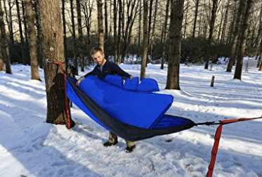 man inserting pad winter camping hammock