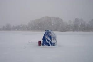 blue ice fishing shelter while snowing