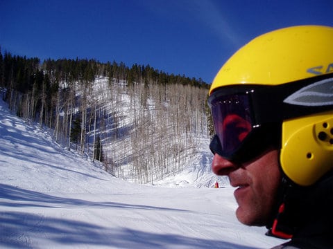 man with yellow helmet on ski slopes