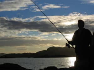 man fishing from shore at dusk